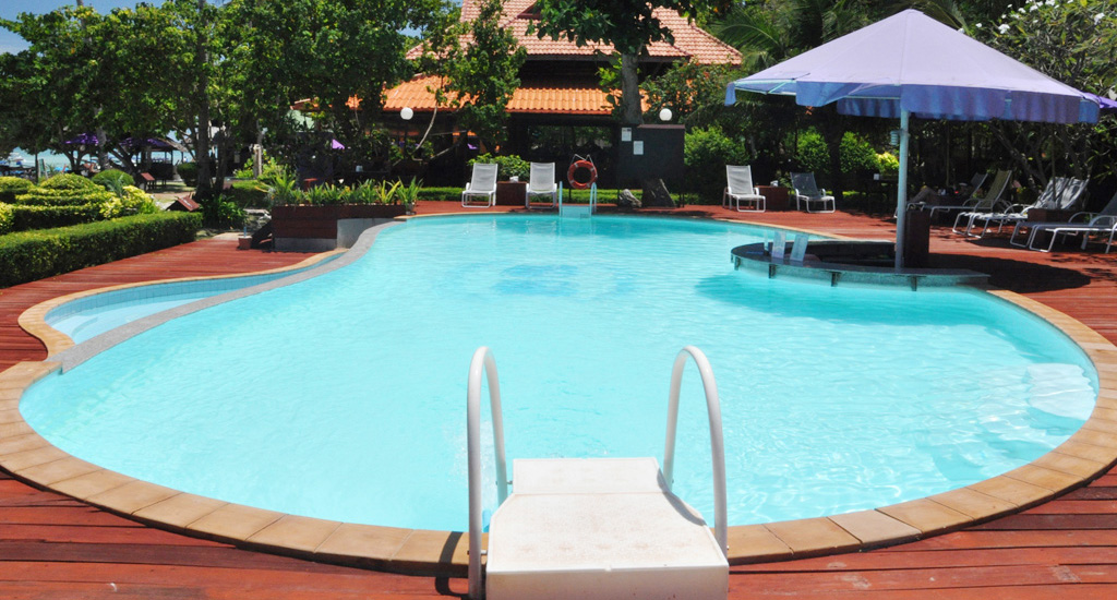 Outdoor swimming pool lies looking over the white powdery sand beach and emerald Blue Ocean.